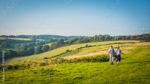 A couple is walking with German Shepherd dog on a coastal pathway in the green British countryside on hills on a hot summer day near Sidmouth, Devon, United Kingdom, UK. Jurassic Coast landscape.  © Vivvi Smak
