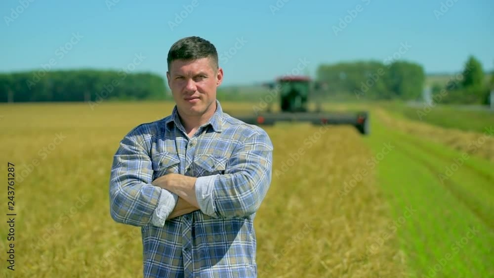 Portrait of happy male farmer man standing at wheat oats rye field of organic farm with harvester combine background, looking at camera grain crop season rural crop farming agronomy harvest harvesting Portrait of happy male farmer man standing at wheat oats rye field of organic farm with harvester combine background, looking at camera grain crop season rural crop farming agronomy harvest harvesting