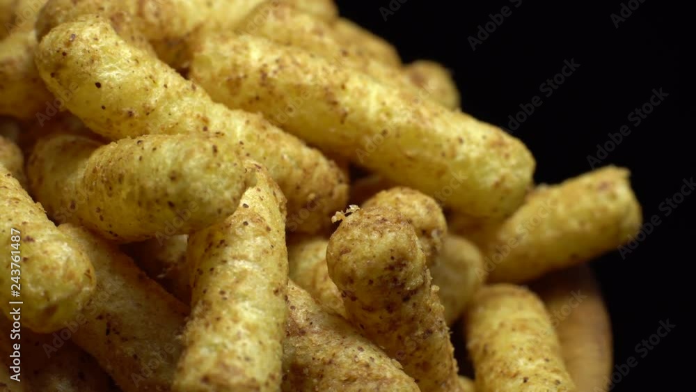 Corn puffs. Rotation. Close up. Puffcorn with peanut flavor. Corn snacks in a bowl. Puffed corn chips. Black background. Studio shot. Unhealthy diet concept. Junk food concept. Corn puffs. Rotation. Close up. Puffcorn with peanut flavor. Corn snacks in a bowl. Puffed corn chips. Black background. Studio shot. Unhealthy diet concept. Junk food concept.