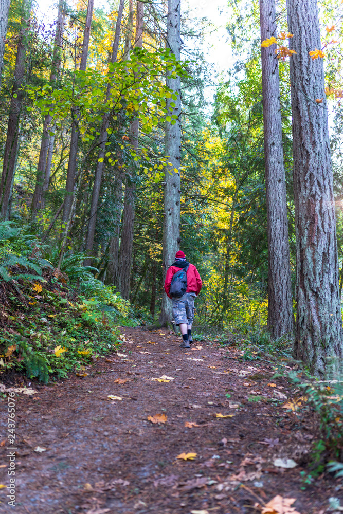 Man with backpack walks along the autumn forest path breathing fresh healthy air