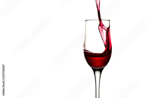 red wine pouring into wine glass isolated. Splash of red wine in a glass on a white background with reflection