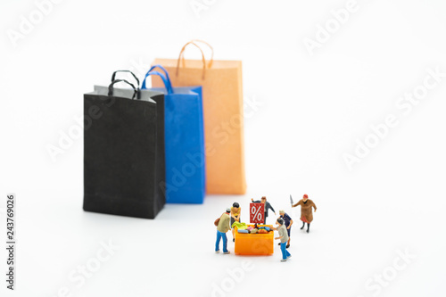 Miniature people, shoppers and display shelf on sale, and shopping bags isolated on white background. Concept of Black Friday, boxing day, year end sales.