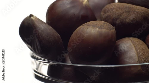 Chestnut. Close up. Heap of raw unroasted sweet chestnut in a bowl in rotation. Food background. Isolated on white, studio shot. Healthy food diet concept. Gastronomy and organic food concept.