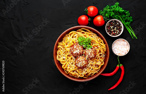 Italian pasta with tomato sauce and meatballs in a plate, dark background