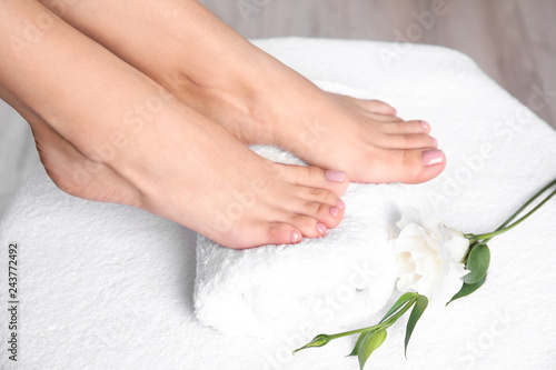 Woman with smooth feet on white towel, closeup. Spa treatment