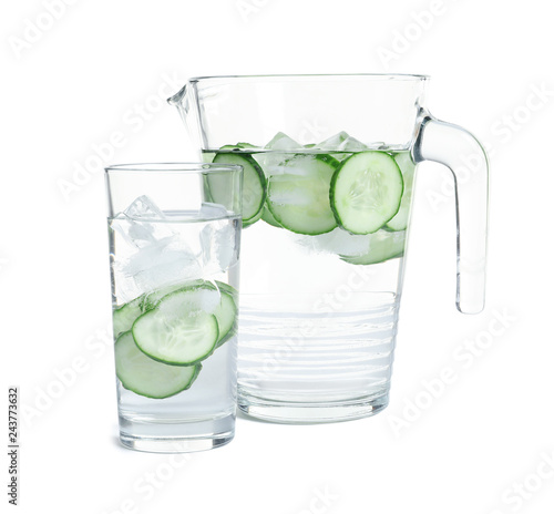 Jug and glass of fresh cucumber water on white background