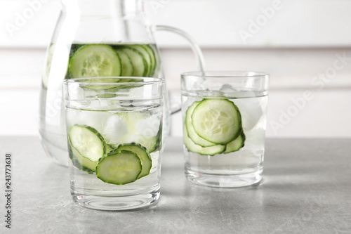 Glasses and jug of fresh cucumber water on table