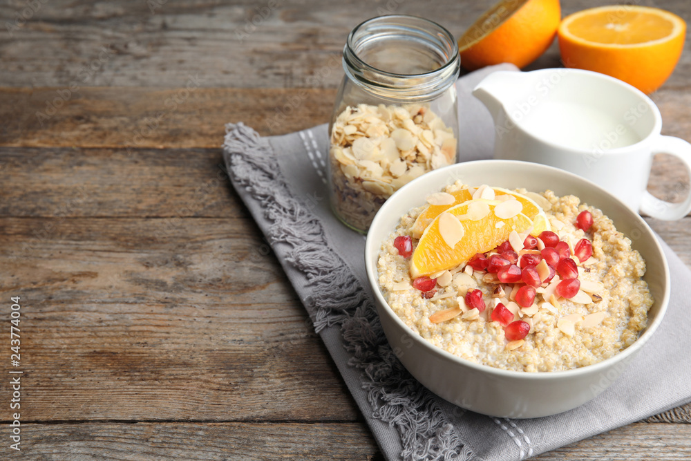 Bowl of quinoa porridge with nuts, orange and pomegranate seeds served for breakfast on wooden table. Space for text Bowl of quinoa porridge with nuts, orange and pomegranate seeds served for breakfast on wooden table. Space for text