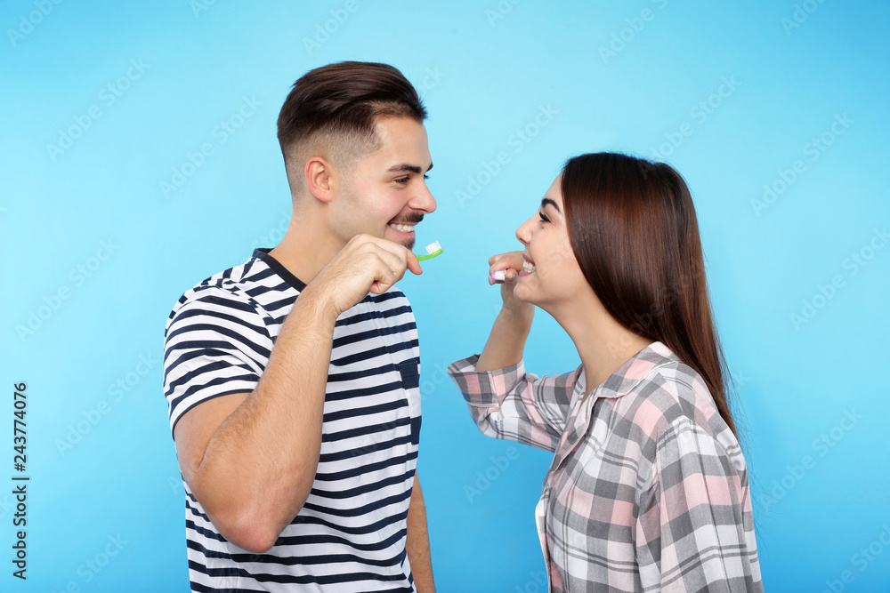 Happy couple brushing teeth on color background Happy couple brushing teeth on color background