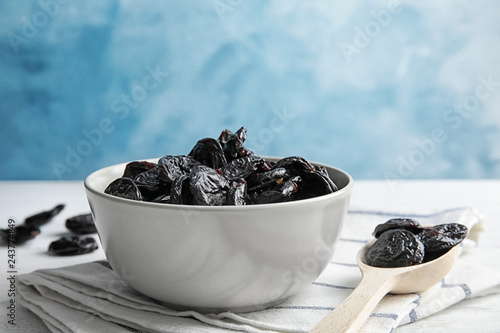 Bowl and spoon of sweet dried plums on table. Healthy fruit