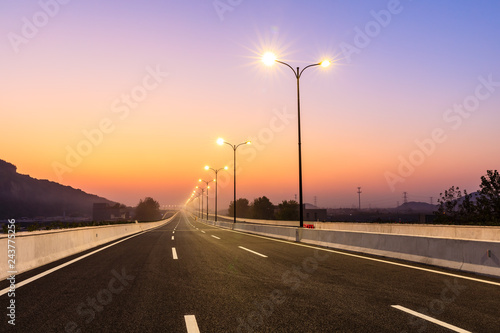 Fotografi City road and bright street lights landscape at sunset