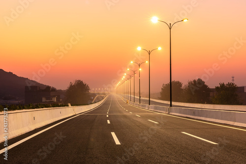 Foto City road and bright street lights landscape at sunset