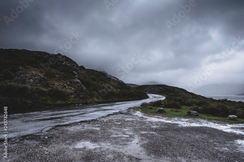 Countryside road wet after rain in scenic mountain valley.Dark, dramatic sky and copy space.