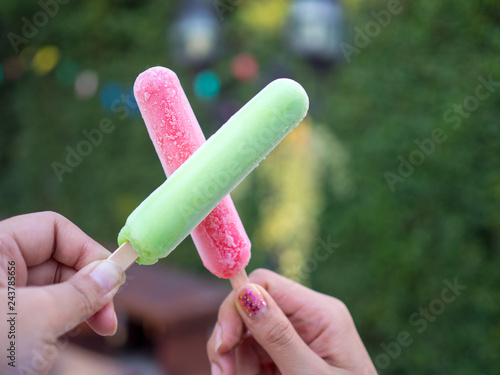 Hand holding green and red popsicle sticks overlapping green background