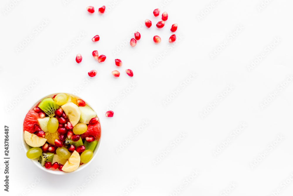Fruit diet concept. Fruit salad with apple, kiwi and pomegranate in bowl on white background top view copy space Fruit diet concept. Fruit salad with apple, kiwi and pomegranate in bowl on white background top view copy space