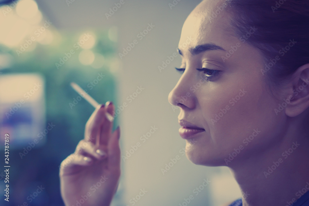 Fototapeta premium Beautiful woman holding a cigarette in her hand outdoors close up