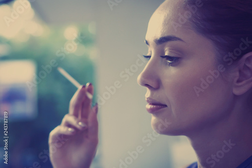 Beautiful woman holding a cigarette in her hand outdoors close up