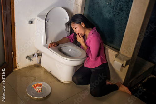 Asian woman throwing up forcing with fingers for vomiting pizza feeling guilty worried about getting fat in bulimia nutrition disorder weight loss obsession photo