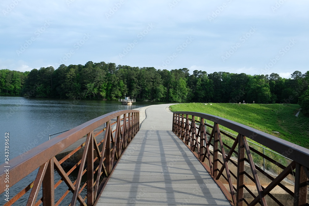 View across the footbridge along the greenway on the dam at Lake Johnson Park in Raleigh North Carolina.
