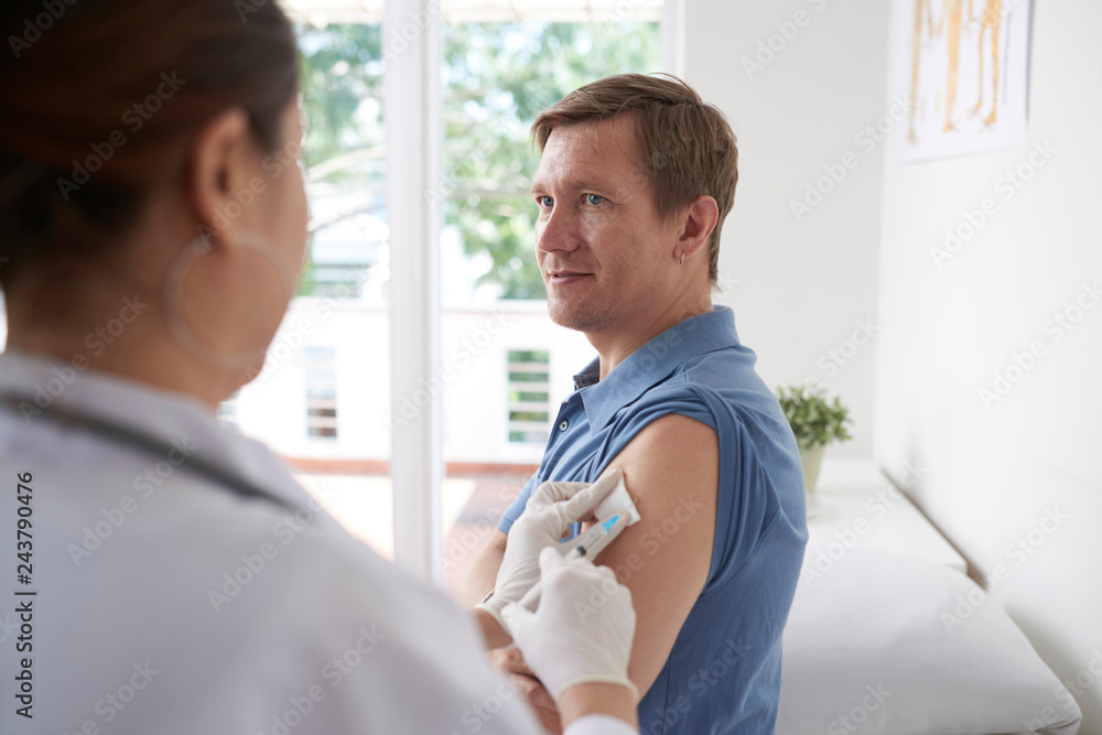 Fototapeta premium Smiling mature man visiting doctor for annual vaccination against influenza