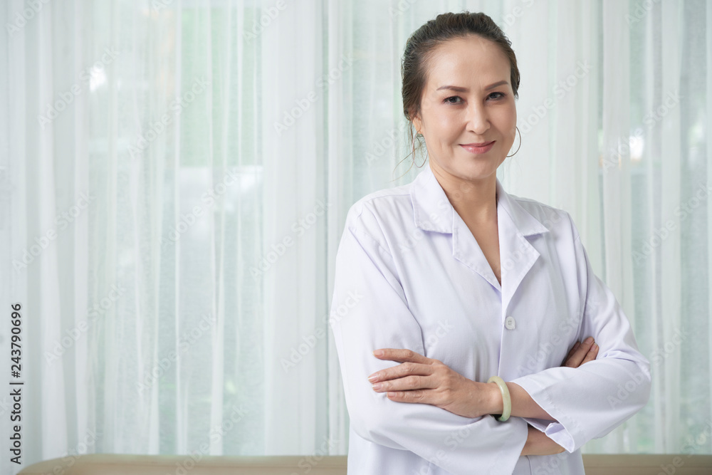 Smiling professional Vietnamese doctor standing with her arms folded Smiling professional Vietnamese doctor standing with her arms folded