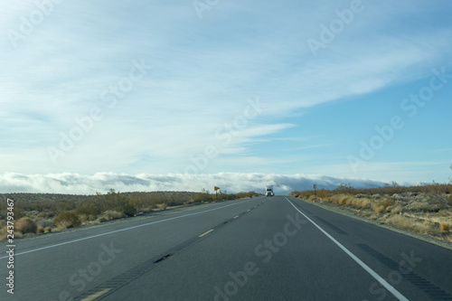 Semi emerges from the fog on a two lane freeway