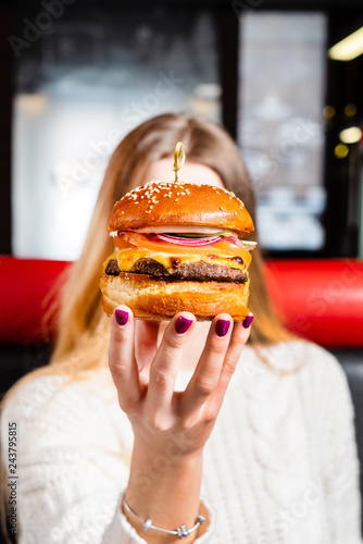 Young girl holding in hands fast food burger with cutlet  cheese and red onion.