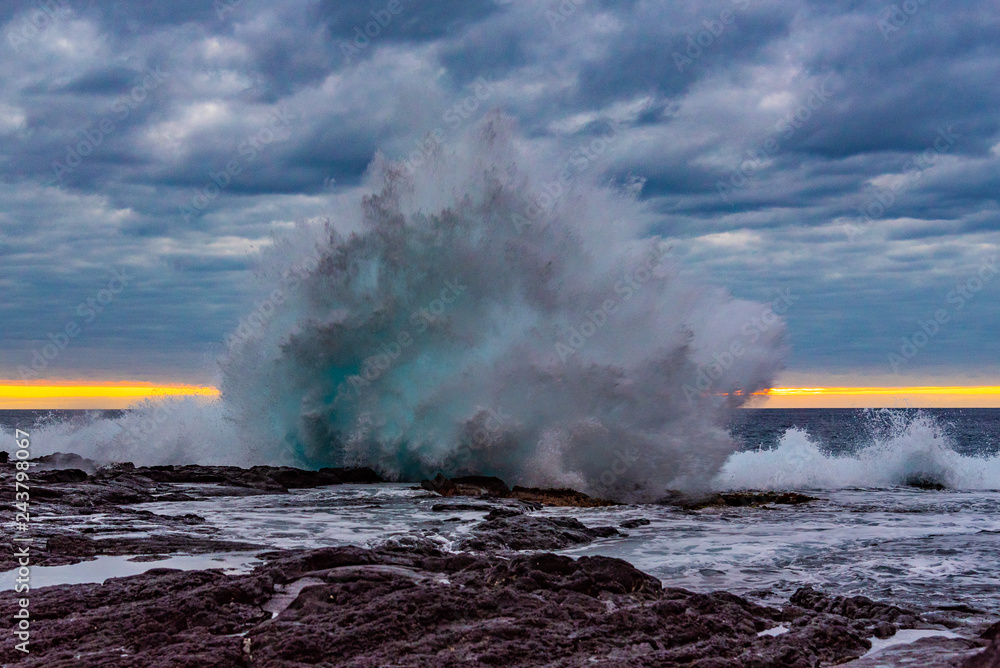 Big waves breaking onshore during sunset over ocean