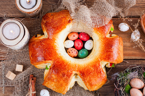 Easter baking in the shape of a wreath with raisins and candied fruits on a wooden table, top view, horizontal photo