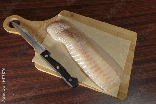 Raw cod fillet on a cutting board. Healthy eating. photo