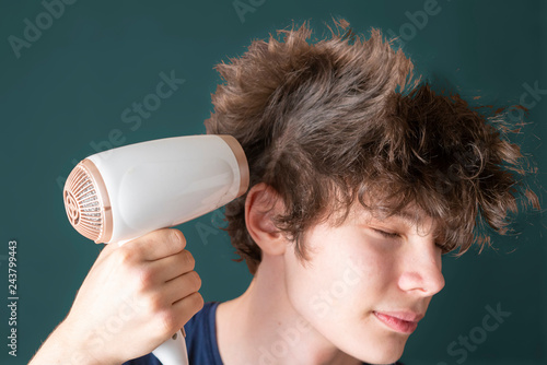 фотографія young male blow his hair with hair dryer isolated b