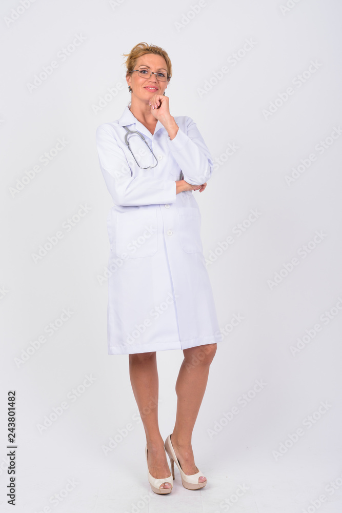 Full body shot of happy mature woman doctor thinking Full body shot of happy mature woman doctor thinking