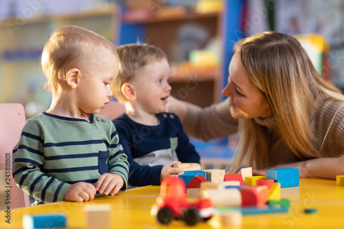 nursery children building blocks with a teacher in preschool playroom