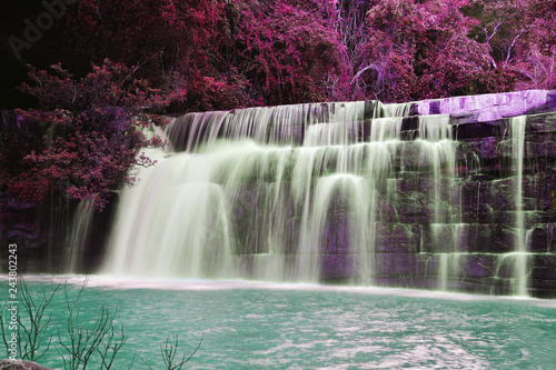 The beautiful waterfall in purple forrest down to emerald green lake. Striking nature. © Orrathai