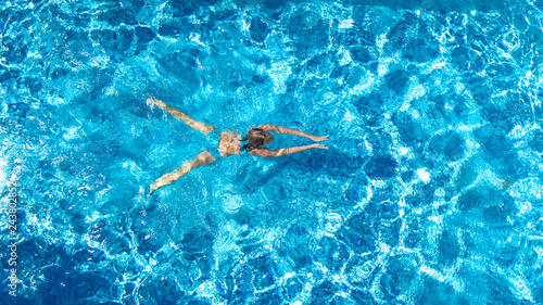 Active girl in swimming pool aerial drone view from above, young woman swims in blue water, tropical vacation, holiday on resort concept 
