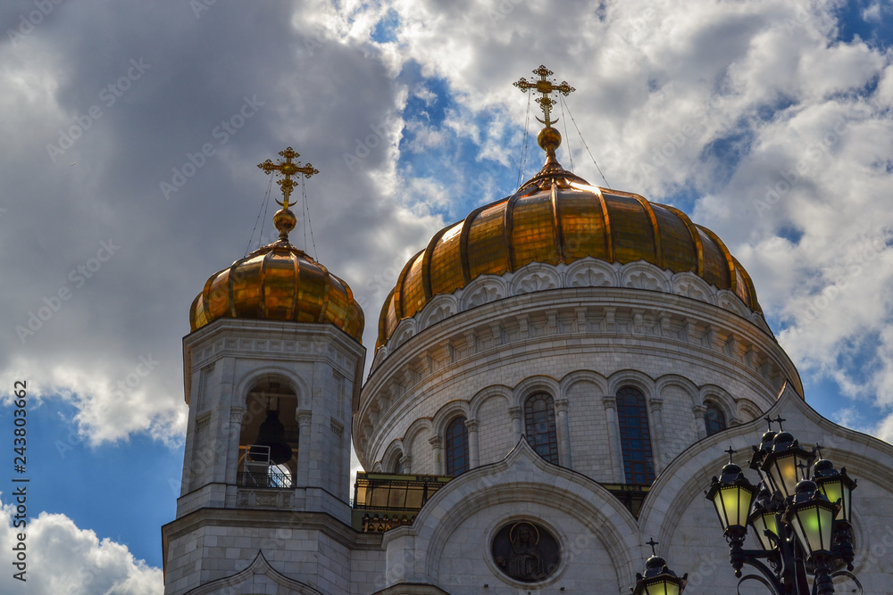 Gilded dome with a cross of the Cathedral of Christ the Savior in Moscow against the blue cloudy sky