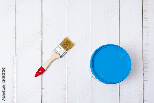 House renovation concept. Brush and a paint bucket on a background of white, shabby wooden planks. Directly above.
