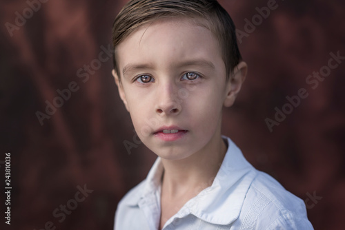 Photo of adorable young happy boy looking at camera.Isolated on the brown background
