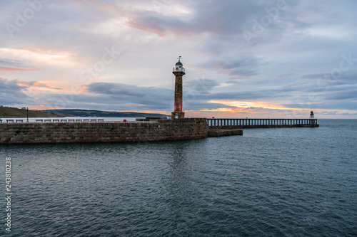 Evening light over the West Pier in Whitby harbour, North Yorkshire, England, UK - seen from the East Pier
