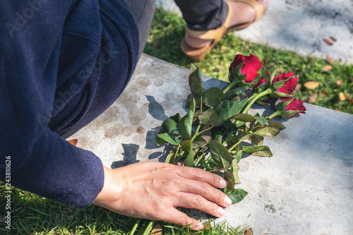  A woman grabbing and holding red roses flower on the ground while sitting in the outdoors
