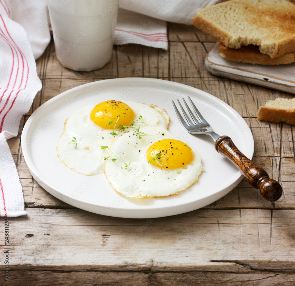 Breakfast of fried eggs, bread toasts and coffee on a wooden table. Rustic style. Breakfast of fried eggs, bread toasts and coffee on a wooden table. Rustic style.