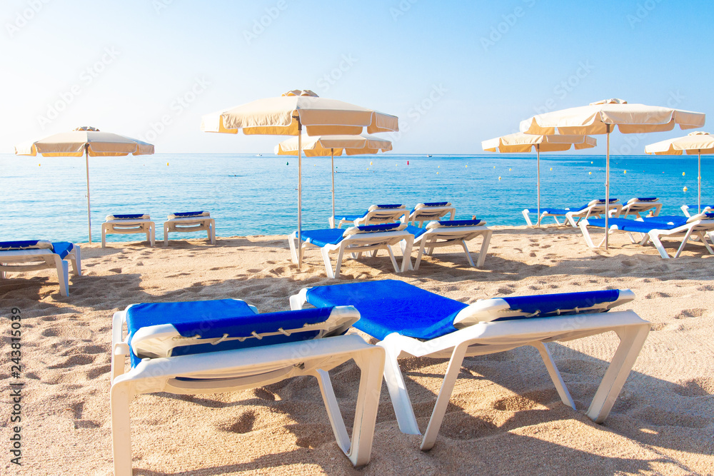 Lloret de Mar beach. Fenals platja. Umbrellas and chaise lounge on spanish beach