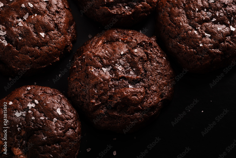 Top view image of soft chocolate cookies with salt flakes on dark background Top view image of soft chocolate cookies with salt flakes on dark background