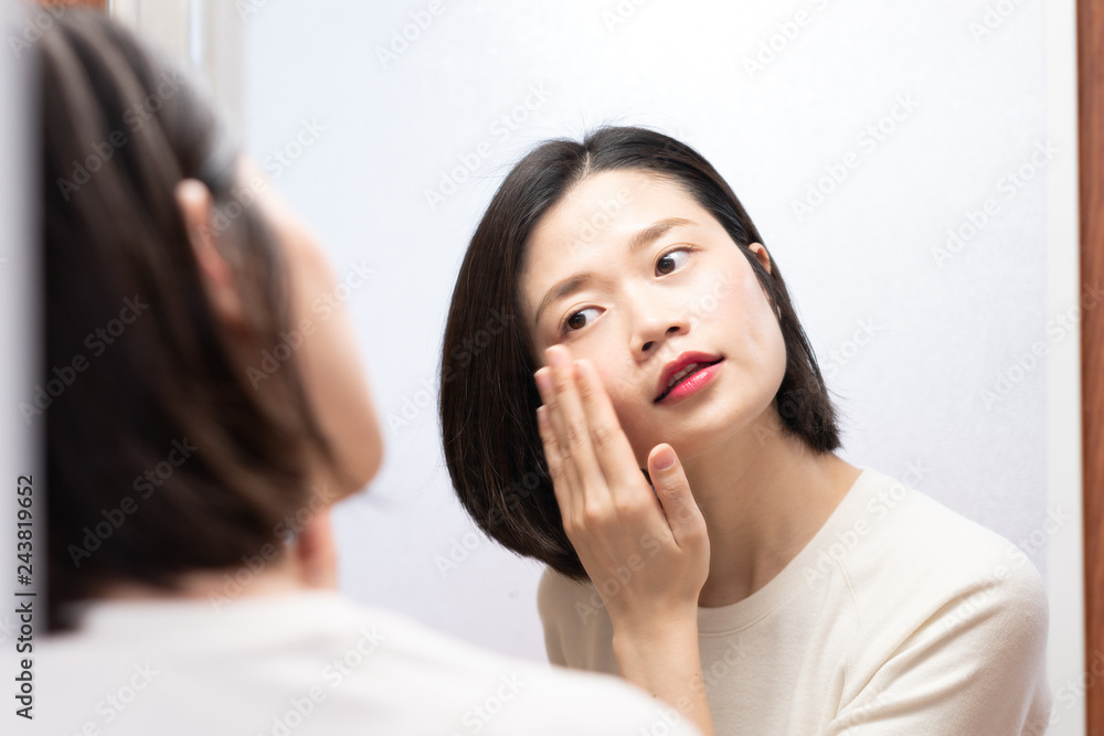 asian female applying makeup and looking in mirror asian female applying makeup and looking in mirror