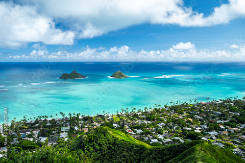 Mokulua islands surrounded by torquise water of the Pacific Ocean and green coast of Oahu, Hawaii