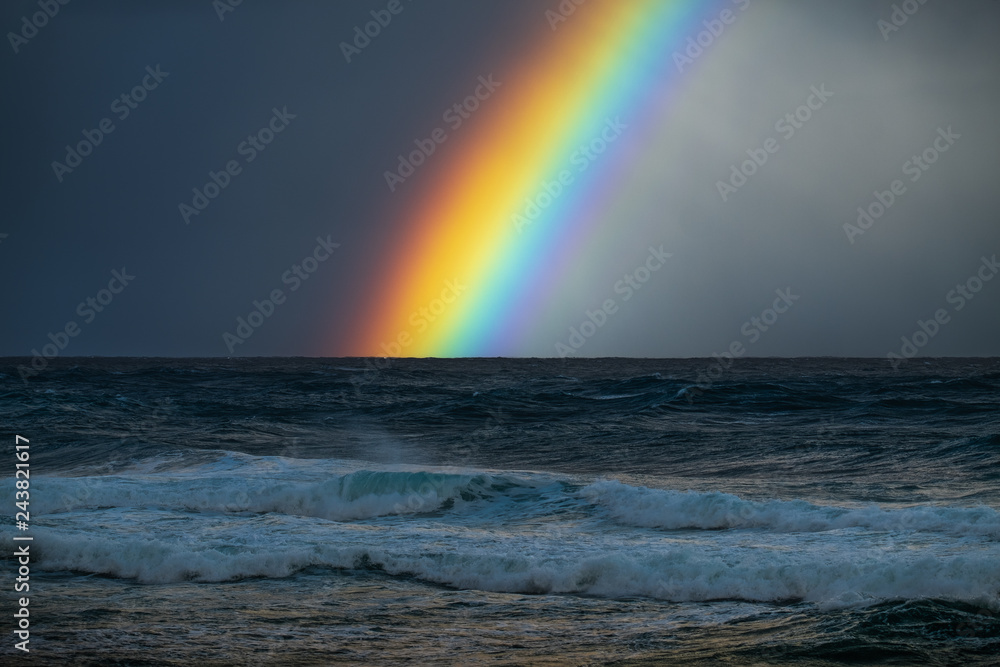 Rainbow over the rough Pacific Ocean with the North Shore waves on the foreground. Oahu, Hawaii