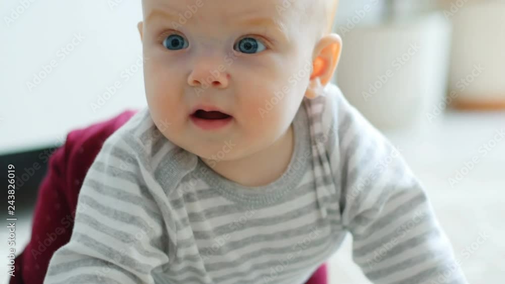The baby girl learns to crawl, the first attempts to crawl. Baby crawls to the camera, smiling and laughing on the floor in the white room The baby girl learns to crawl, the first attempts to crawl. Baby crawls to the camera, smiling and laughing on the floor in the white room
