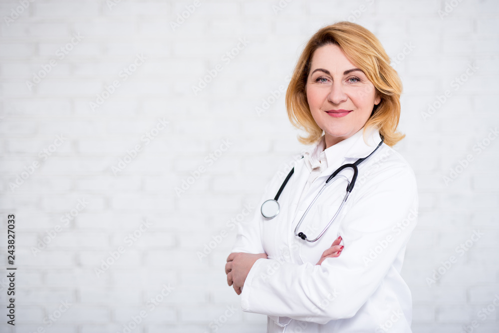 mature female doctor or nurse posing over white wall with copy space mature female doctor or nurse posing over white wall with copy space