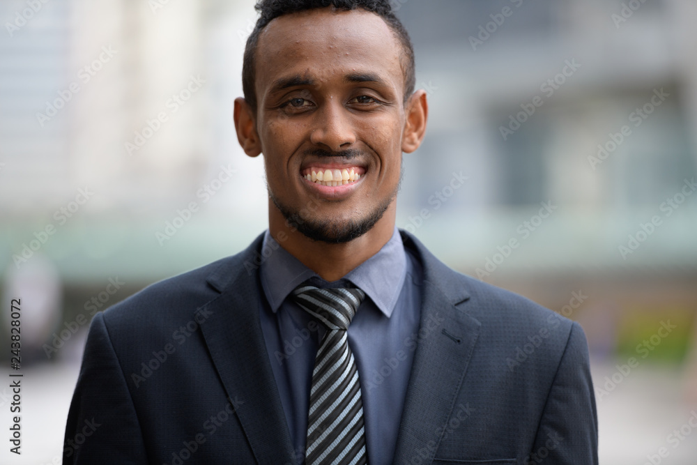 Face of happy young African businessman smiling outdoors Face of happy young African businessman smiling outdoors