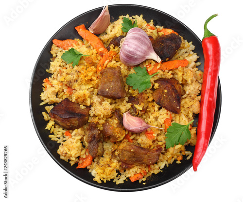 pilaf with meat and chili pepper on black plate isolated on white background. top view